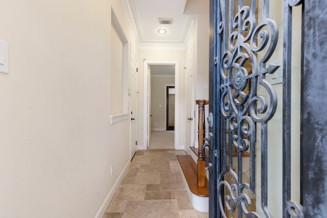 corridor with crown molding, stone tile flooring, and baseboards
