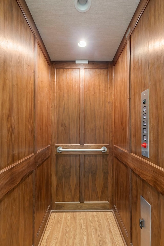 elevator featuring wooden walls and a textured ceiling