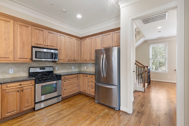 kitchen featuring appliances with stainless steel finishes, ornamental molding, light wood-type flooring, backsplash, and baseboards