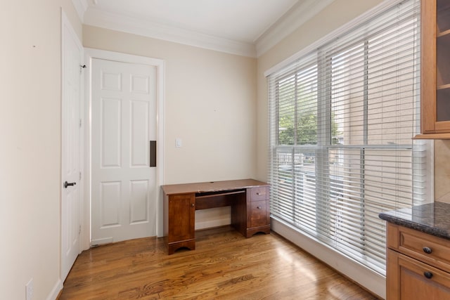 unfurnished office featuring light wood-type flooring and crown molding