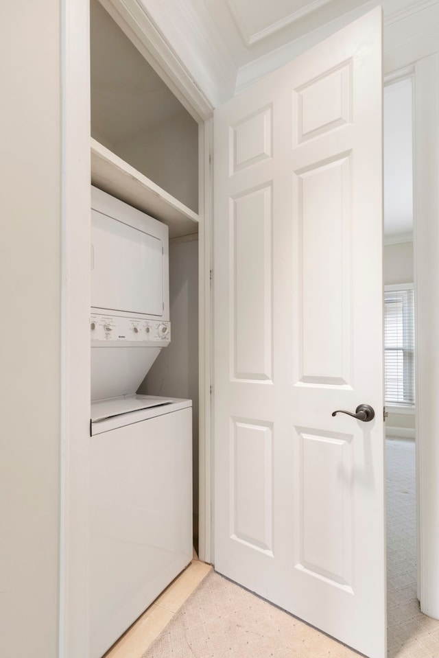 washroom with stacked washing machine and dryer and crown molding
