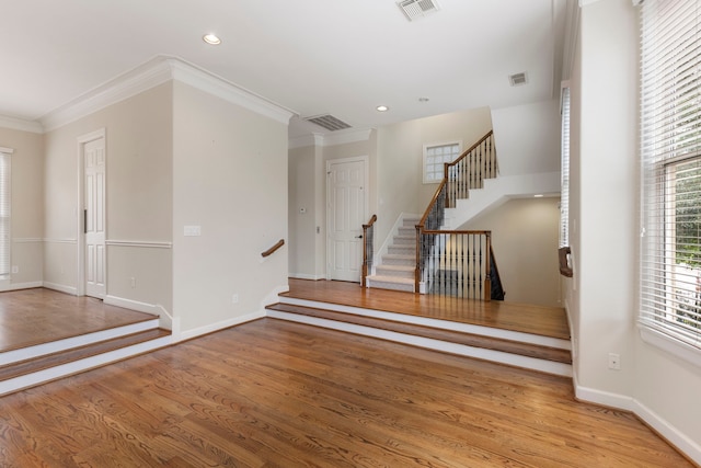 empty room with crown molding, stairs, wood finished floors, baseboards, and recessed lighting