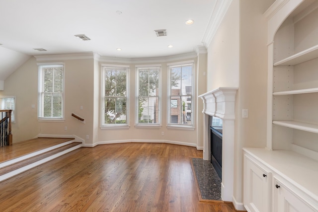 unfurnished living room featuring a fireplace, light wood-style flooring, plenty of natural light, built in features, and ornamental molding