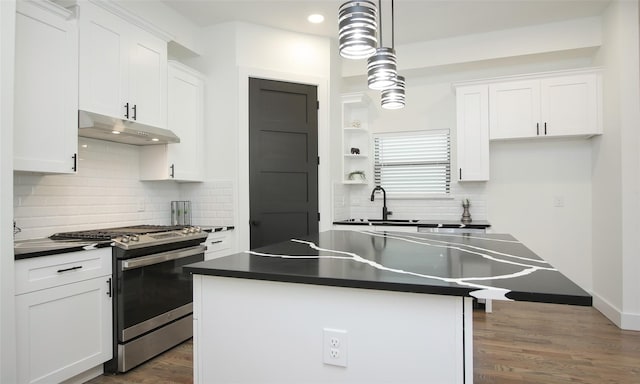 1224 Johnston St, Houston, TX 77022 - kitchen with gas stove, under cabinet range hood, dark countertops, white cabinets, and a sink