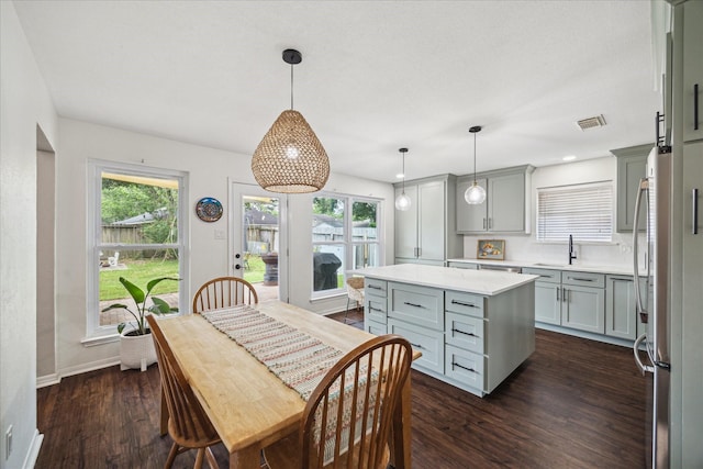 kitchen with a sink, dark wood-style floors, gray cabinetry, baseboards, and a kitchen island
