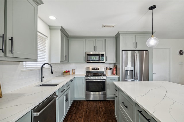 kitchen featuring stainless steel appliances, gray cabinetry, a sink, and decorative backsplash