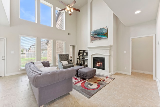 27935 Chiapas Dr, Spring, TX 77386 - living area with a glass covered fireplace, ceiling fan, a towering ceiling, light tile patterned floors, and baseboards