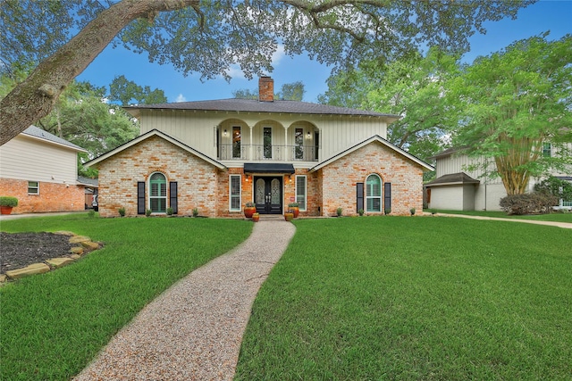 12443 Honeywood Trl, Houston, TX 77077 - view of front of home featuring a front yard, a balcony, brick siding, french doors, and a chimney