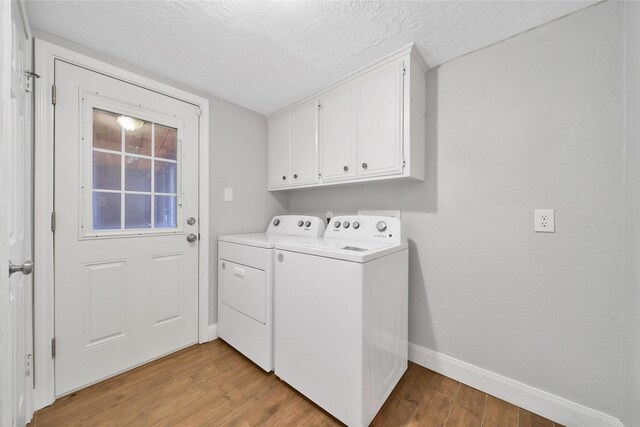 12443 Honeywood Trl, Houston, TX 77077 - clothes washing area featuring washer and clothes dryer, baseboards, light wood finished floors, cabinet space, and a textured ceiling