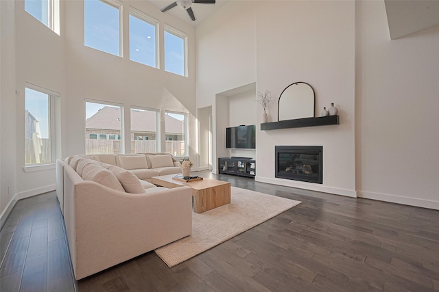 29851 Aaron River Trl, Fulshear, TX 77441 - living room featuring a high ceiling, ceiling fan, dark wood finished floors, baseboards, and a glass covered fireplace