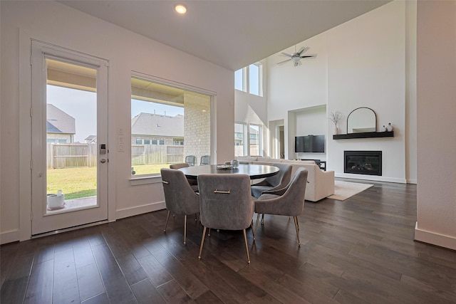 29851 Aaron River Trl, Fulshear, TX 77441 - dining area featuring a glass covered fireplace, dark wood-style floors, ceiling fan, and baseboards