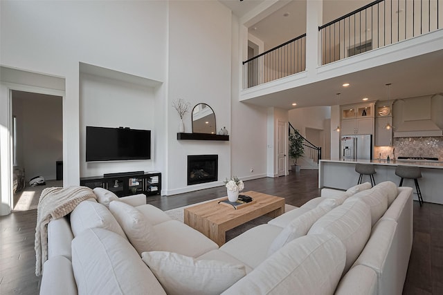 29851 Aaron River Trl, Fulshear, TX 77441 - living room with a towering ceiling, dark wood-style floors, a glass covered fireplace, baseboards, and recessed lighting