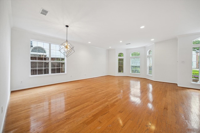 empty room featuring plenty of natural light, light wood-style floors, recessed lighting, crown molding, and baseboards