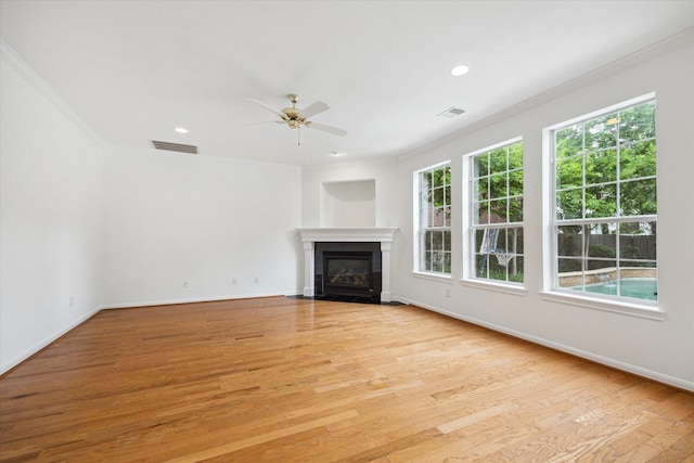 unfurnished living room featuring ornamental molding, a ceiling fan, a fireplace with flush hearth, light wood finished floors, and baseboards