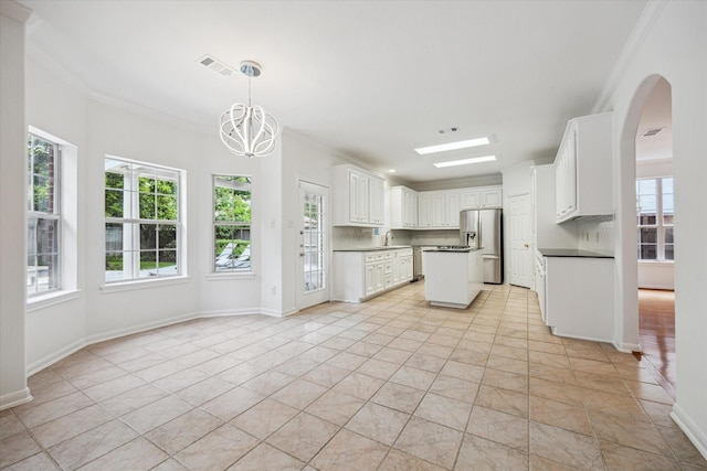 kitchen featuring stainless steel fridge, ornamental molding, dark countertops, a chandelier, and light tile patterned floors