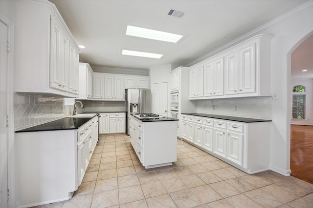 kitchen featuring dark countertops, arched walkways, white appliances, and crown molding