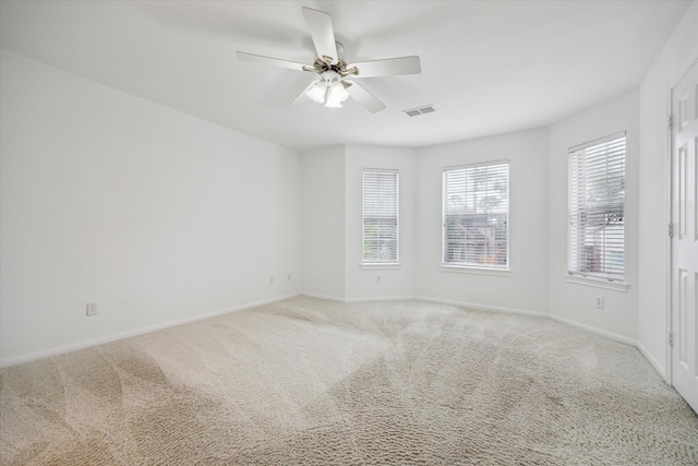 empty room featuring light carpet, a ceiling fan, and baseboards