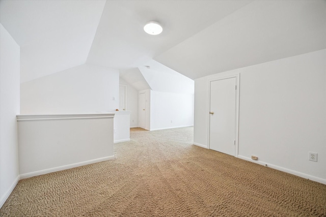 additional living space with light colored carpet, vaulted ceiling, and baseboards