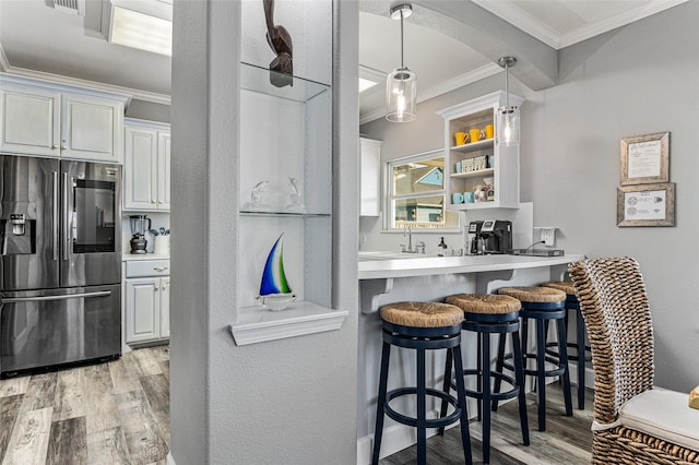 2296 Martinique, Crystal Beach, TX 77650 - kitchen featuring stainless steel fridge with ice dispenser, crown molding, light wood-style flooring, a kitchen bar, and light countertops