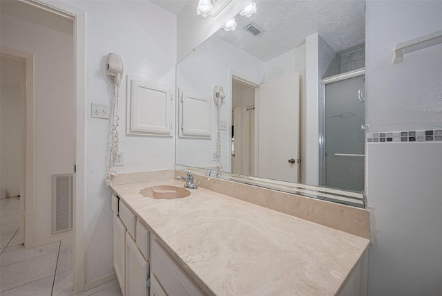 bathroom with tile patterned flooring, vanity, a shower with door, and a textured ceiling