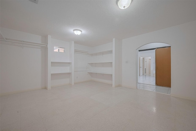 spacious closet with tile patterned floors and arched walkways
