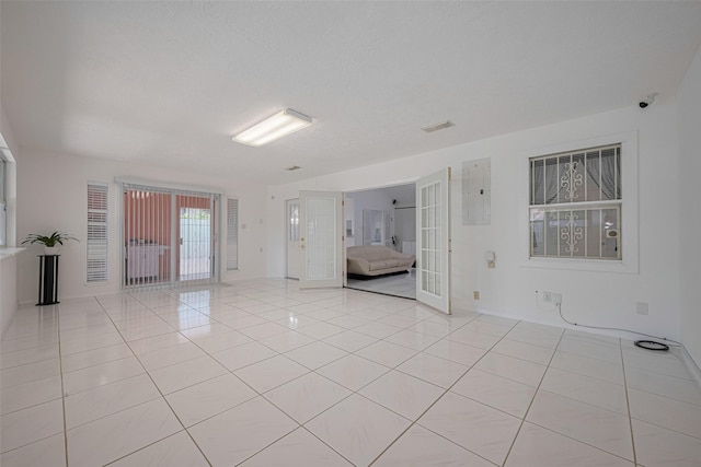unfurnished room with light tile patterned flooring, electric panel, baseboards, and french doors