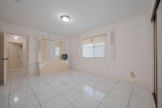 empty room with light tile patterned floors and a textured ceiling