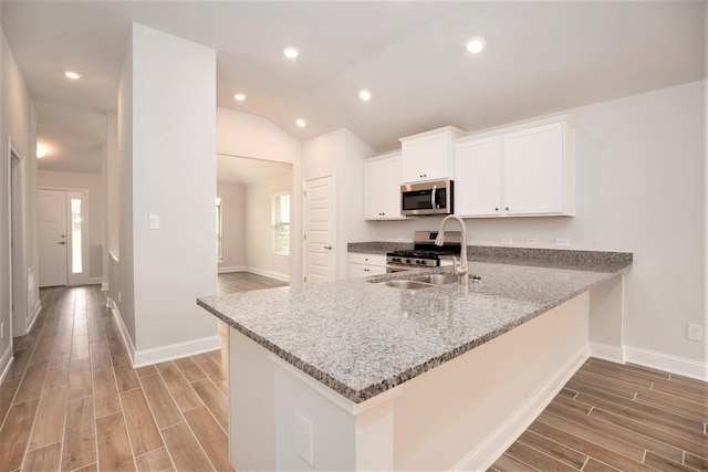 4401 E Bayou Maison Cir, Dickinson, TX 77539 - kitchen featuring appliances with stainless steel finishes, a sink, light stone countertops, light wood-style floors, and lofted ceiling