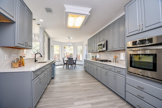 20011 Polly Creek Way, Katy, TX 77450 - kitchen featuring gray cabinets, stainless steel appliances, a sink, light wood finished floors, and light countertops