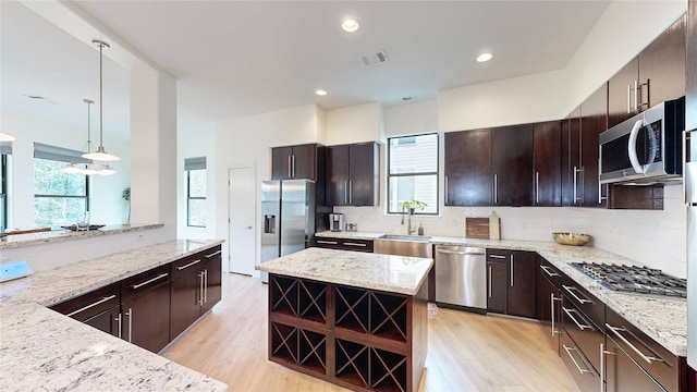 kitchen with appliances with stainless steel finishes, healthy amount of natural light, light wood-type flooring, backsplash, and recessed lighting
