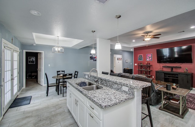 114 Dr Martin Luther King Jr Dr, La Porte, TX 77571 - kitchen with a tray ceiling, a sink, white cabinets, open floor plan, and light stone countertops