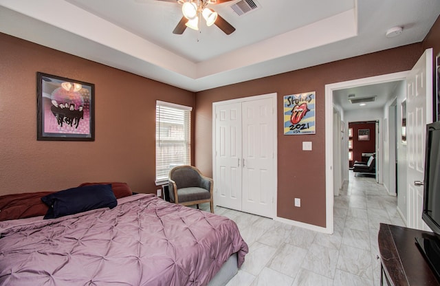 114 Dr Martin Luther King Jr Dr, La Porte, TX 77571 - bedroom featuring a tray ceiling, baseboards, a closet, a ceiling fan, and light marble finish flooring