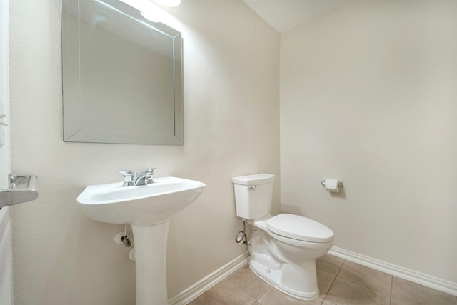 bathroom featuring toilet, baseboards, tile patterned flooring, and a sink