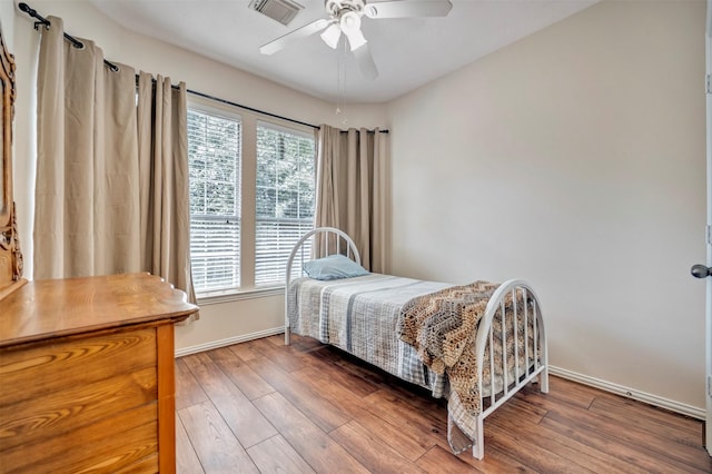 bedroom with multiple windows, baseboards, and wood finished floors