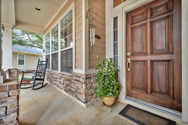 property entrance featuring a porch and stone siding