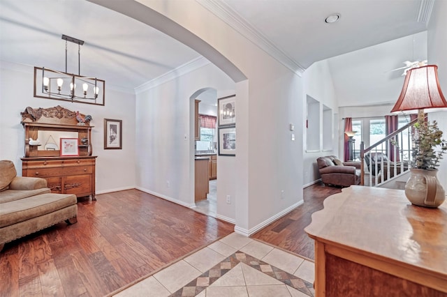 foyer with arched walkways, crown molding, baseboards, light tile patterned floors, and inlaid floor details