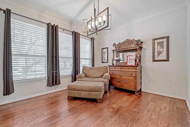 living area featuring a chandelier, wood finished floors, ornamental molding, and baseboards