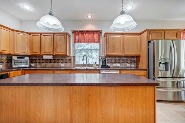kitchen featuring stainless steel appliances, a sink, dark countertops, a kitchen island, and decorative backsplash