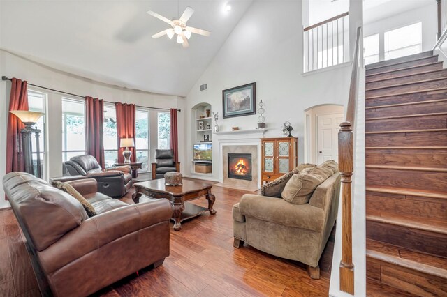 living room with high vaulted ceiling, stairway, built in features, ceiling fan, and a high end fireplace