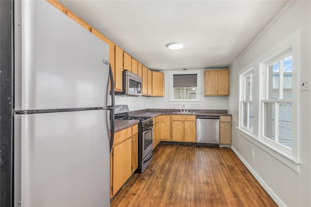 1614 Ursuline St, Galveston, TX 77550 - kitchen with stainless steel appliances, dark countertops, dark wood-style flooring, a sink, and baseboards
