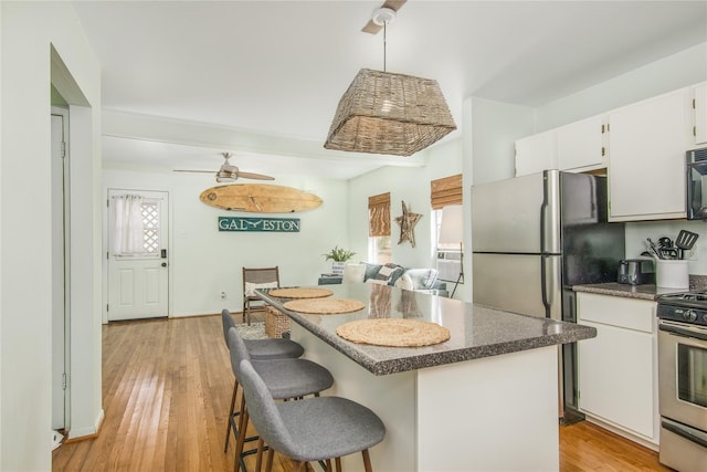 1614 Ursuline St, Galveston, TX 77550 - kitchen featuring appliances with stainless steel finishes, ceiling fan, a kitchen island, light wood finished floors, and white cabinets