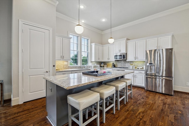 2729 Cohn St, Houston, TX 77007 - kitchen with appliances with stainless steel finishes, ornamental molding, white cabinetry, a kitchen island, and decorative backsplash