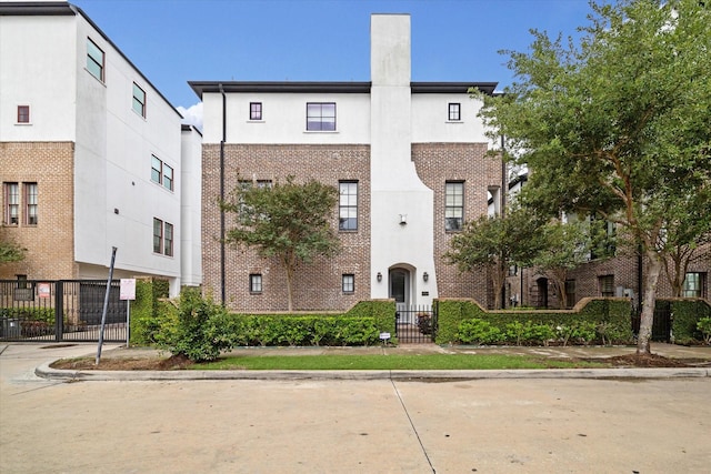 2729 Cohn St, Houston, TX 77007 - townhome / multi-family property with stucco siding, a chimney, brick siding, and a gate