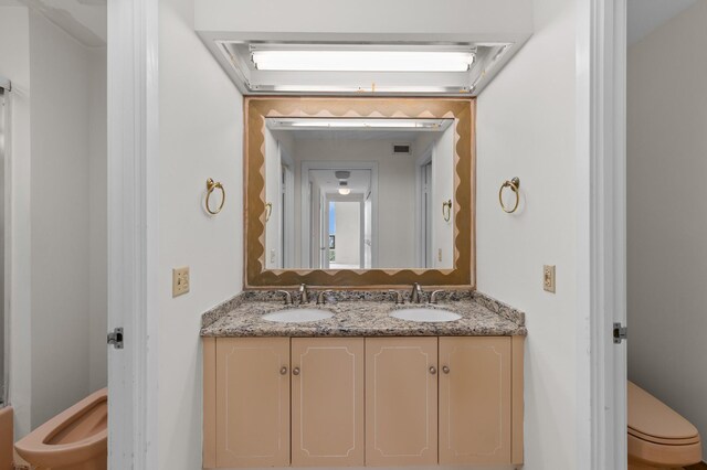 bathroom featuring toilet and double vanity