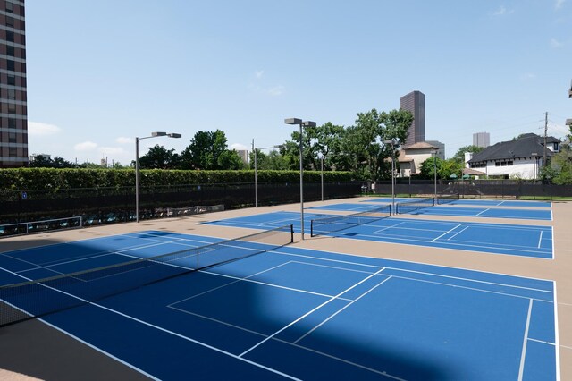 view of tennis court with community basketball court and fence