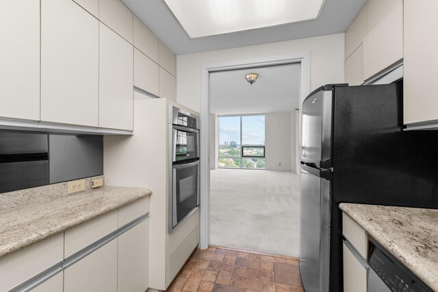 kitchen with appliances with stainless steel finishes, light stone finish floors, and white cabinetry