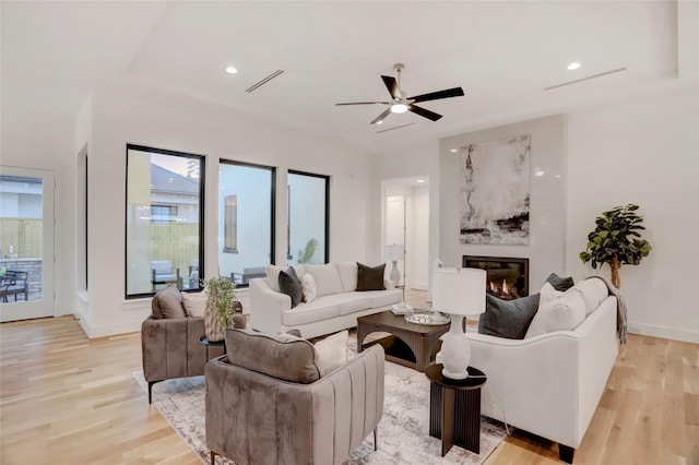 2702 Westgrove Ln, Houston, TX 77027 - living area featuring light wood-style flooring, a glass covered fireplace, a ceiling fan, and baseboards
