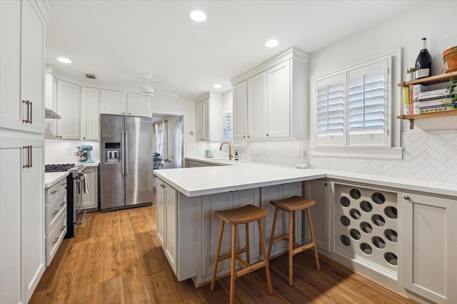 741 E 13th 1/2 St, Houston, TX 77008 - kitchen featuring stainless steel appliances, a peninsula, decorative backsplash, a kitchen bar, and recessed lighting