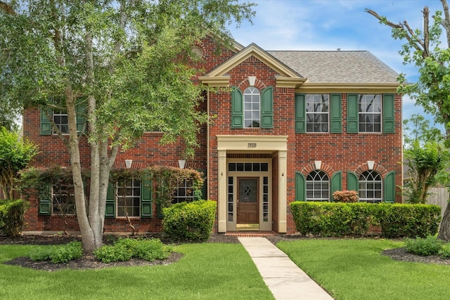 1301 Wilderness Pines Dr, Friendswood, TX 77546 - colonial inspired home featuring brick siding, a front yard, and a shingled roof