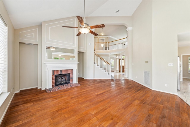 1301 Wilderness Pines Dr, Friendswood, TX 77546 - unfurnished living room with ceiling fan, wood finished floors, a brick fireplace, high vaulted ceiling, and baseboards